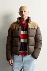 Cazadora puffer relaxed fit color marrón con canesú superior en tono tostado de acabado aterciopelado. Cuenta con cuello subido, manga larga, bolsillos de vivo en la cadera, acabados en elástico y cierre frontal con cremallera.