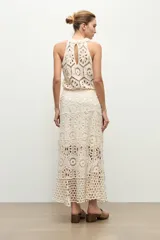 Falda midi beige de tejido crochet con diseño de motivos geométricos perforados.