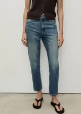 Pantalón jeans de tiro alto y corte mom-fit, color azul con lavado claro, con trabillas para cinto, cinco bolsillos y cierre frontal con cremallera y botón.