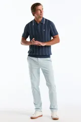 Chomba de punto color azul con finas rayas verticales blancas, cuello polo con botones y mangas cortas.