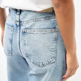 Pantalón jean de corte globo y tiro alto, en tono azul claro con efecto lavado. Presenta diseño amplio de perneras curvas y costuras decorativas.