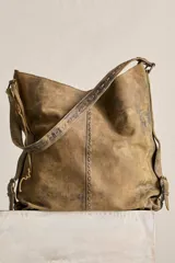 Cartera tote de cuero suave color marrón con efecto envejecido, cuerpo blando, caída relajada, correa ancha fija al hombro y costuras decorativas pespunteadas.