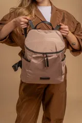 Mochila urbana de diseño compacto en color negro, confeccionada en nylon resistente. Cuenta con un compartimento principal con cierre, bolsillo frontal con cierre y correas ajustables con detalle de marca.