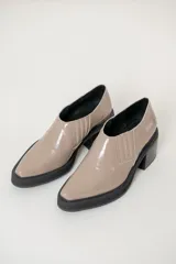 Botines color beige de charol, con elástico a los costados, suela track color negro y taco cuadrado.