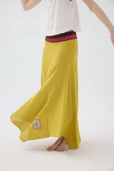 Falda larga de punto color mostaza, con cortes asimétricos, distintos puntos texturizados, ruedo irregular y pretina elástica con detalles en tono contrastante.
