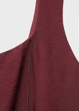Vestido midi color bordó con diseño evasé, tirantes anchos y cuello cuadrado. Presenta costuras decorativas verticales y cierre de cremallera en la parte posterior.