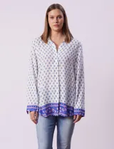 Camisa blanca con estampado floral en azul, de manga larga y cuello con solapa.