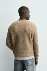 Jersey de punto regular fit, confeccionado en una mezcla de lana y fibra de alpaca. Presenta cuello redondo, manga larga y acabados en rib en puños y bajo.