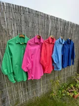 Camisa oversize color fucsia, de lino, con cuello camisero, cierre frontal con botones y mangas largas abullonadas con puños elásticos.