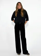Pantalon de corte recto y tiro alto, confeccionado en pana negra con costuras verticales decorativas en el frente.