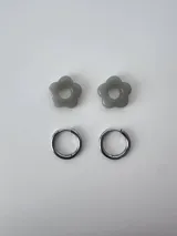 Aros de acero quirúrgico hipoalergénico con dije en forma de flor color gris.