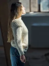 Sweater tejido a crochet color crudo, con cuello redondo, mangas largas y hombros abullonados.