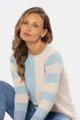 Buzo de tejido fino confeccionado en algodón, con diseño de bloques de color y rayas. Presenta un bloque azul claro en el hombro izquierdo, un bloque beige en el centro y rayas horizontales beige y azul claro en el hombro y brazo derechos. La manga izquierda es de color lila.