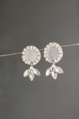 Par de aros colgantes con base circular plateada con strass y dije colgante con forma de flor de cristal.