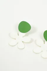 Aros colgantes con diseño de flor blanca y pieza superior circular en color verde.