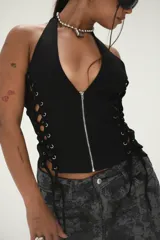 Top negro tipo corset con escote halter, cierre frontal con cremallera y cordones ajustables en los laterales.