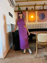Vestido midi lila con cuello halter y aberturas laterales en la cintura.