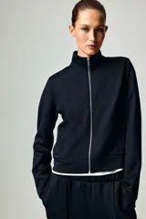Campera deportiva corta de punto grueso con leve brillo, cuello elevado, cierre frontal y bolsillos laterales insertados.