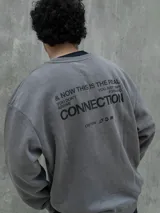 Buzo gris con cuello redondo, mangas largas y puños y bajo acanalados. Estampado frontal con el logo "Osten" y la frase "A mindset of becoming".