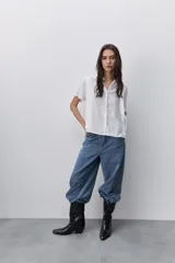 Camisa negra de manga corta, con cuello mao y cierre frontal de botones, de silueta amplia y tejido liviano con textura sutil.
