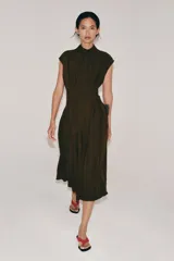 Vestido midi de Zara Woman Collection, confeccionado en mezcla de viscosa y lyocell. Presenta cuello perkins con lazada frontal, diseño sin mangas, pliegues en la cintura y cierre posterior con abertura y botones.
