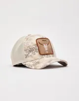 Gorra de béisbol trucker Goorin Bros con diseño de calavera de toro y la palabra "DEAD" en un parche frontal. La parte delantera es de color beige con estampado difuminado y la parte trasera es de malla color beige.