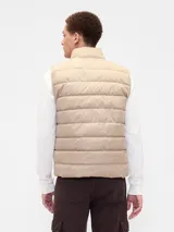 Chaleco puffer acolchado de color beige, con cierre frontal de cremallera, cuello alto y logo de la marca bordado en el pecho.