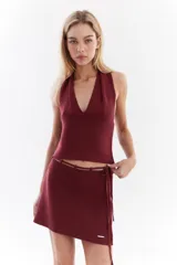 Top bordó de punto con lurex, escote en V profundo estilo halter y diseño sin mangas.