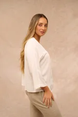 Blusa color crudo de mangas 3/4, escote en V con abotonadura frontal y sutiles pliegues en la parte delantera.