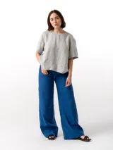 Pantalón de lino azul con corte amplio, cintura elastizada con cordón ajustable, dos bolsillos laterales y un bolsillo trasero.