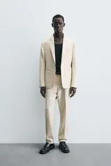 Pantalón de corte recto confeccionado en tejido con lana, color beige. Presenta bolsillos frontales, bolsillos traseros de vivo y cierre frontal con cremallera y botón.