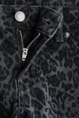 Jeans de tiro bajo con corte ajustado hasta el muslo y acampanado desde la rodilla. El tejido es de denim elástico con estampado de leopardo en tonos grises oscuros. Presenta cierre y botón, bolsillos delanteros decorativos y bolsillos abiertos traseros.