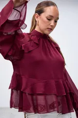 Blusa de gasa color bordó con cuello alto, mangas largas con volados y diseño de capas con volados en el cuerpo.