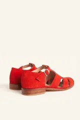 Sandalias de gamuza color marrón, estilo romano con diseño en T, tiras con aberturas laterales y cierre de hebilla metálica en el tobillo. Cuenta con tacón bajo de madera.