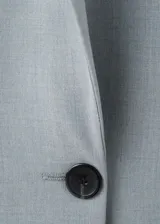 Blazer de corte sastrero en color gris azulado, con cierre frontal de un botón, solapas clásicas y bolsillos laterales con solapa.