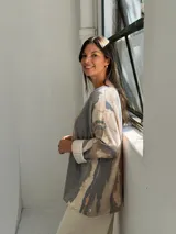 Sweater de punto con diseño abstracto de rayas verticales en tonos gris, beige y terracota. Presenta cuello en V, corte holgado y mangas largas con puños vueltos.