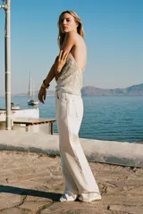 Top blanco con lentejuelas plateadas, de cuello halter y espalda descubierta.