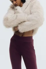 Pantalón de tiro alto confeccionado en punto roma, con diseño ajustado en la parte superior y piernas acampanadas. Presenta bolsillos insertados decorativos en la parte frontal.
