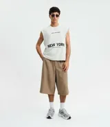 Musculosa masculina de corte boxy fit, confeccionada en algodón. Presenta cuello redondo, hombros ligeramente ampliados y acabado deshilachado en el ruedo. Cuenta con estampa frontal con la frase 'Urban Scene Trends' y el texto 'New York Manhattan 1974' en el centro.