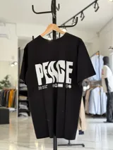 Remera oversize blanca de manga corta, con gran estampado negro en la espalda con la palabra 'Peace' y símbolos gráficos.