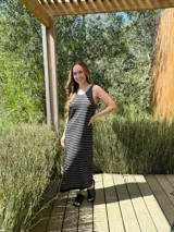 Vestido largo de punto, negro con rayas horizontales blancas, corte recto y sin mangas.