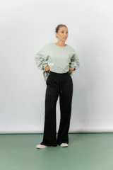 Pantalón negro de silueta amplia y caída fluida, con cintura alta elastizada y lazo regulable con terminaciones metálicas. El calce wide leg genera movimiento y alarga visualmente la pierna.