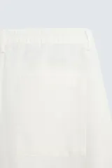 Bermuda de algodón color blanco, de corte relajado, con cintura elástica, bolsillos frontales y bolsillos traseros de plastrón. Cierre frontal con cremallera y botón.