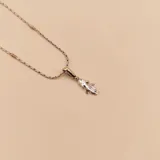 Conjunto compuesto por una cadena de eslabones de plata con detalles en oro y un dije colgante con forma de niña en plata.