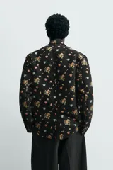 Blazer de hombre de corte relaxed fit confeccionado en tejido jacquard negro con estampado floral multicolor. Tiene cuello con solapas de muesca, manga larga con puños abotonados, bolsillo de vivo en el pecho, bolsillos de solapa en la cadera, bolsillo interior, abertura en el centro de la espalda y cierre frontal con botones.