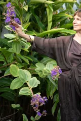 Conjunto de dos piezas color negro, compuesto por un pantalón ancho de tiro alto con detalle de encaje en el ruedo y una blusa holgada de manga larga con escote drapeado y nudo frontal.