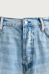Jeans de corte regular cropped confeccionados en denim ligero de algodón. Presentan un diseño de cinco bolsillos con efecto lavado, tiro medio y cierre frontal con botones.