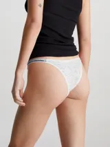 Colaless de tiro medio, color blanco, confeccionado en encaje semitransparente con patrón de leopardo. Presenta ribetes elásticos con el logotipo de Calvin Klein.