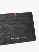 Tarjetero de piel negro de la marca Tommy Hilfiger, con acabado granulado, ranuras exteriores para tarjetas, detalle de cinta tricolor y logo metálico.