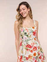 Vestido midi evasé de lino estampado con diseño floral multicolor sobre base beige. Cuenta con escote cuadrado, tirantes anchos y cierre invisible en la espalda.
